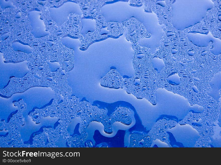 Sunlit water droplet on blue car after rain shower. Sunlit water droplet on blue car after rain shower