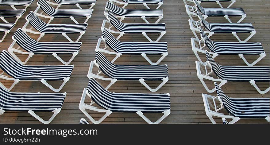 Chairs lined up and ready for the sunbathers on the deck of a cruise ship. Chairs lined up and ready for the sunbathers on the deck of a cruise ship.