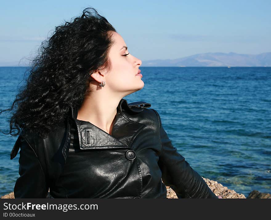 A brunette young beautiful woman with green eyes by the sea. A brunette young beautiful woman with green eyes by the sea