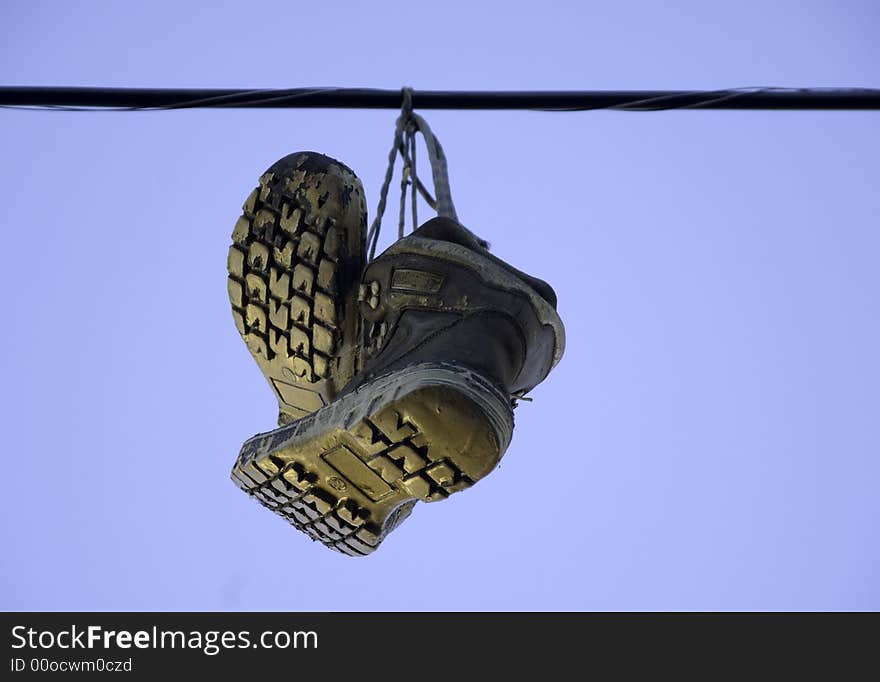 Workboots hanging from a power line gleam in the glow of the late afternoon sun. Workboots hanging from a power line gleam in the glow of the late afternoon sun