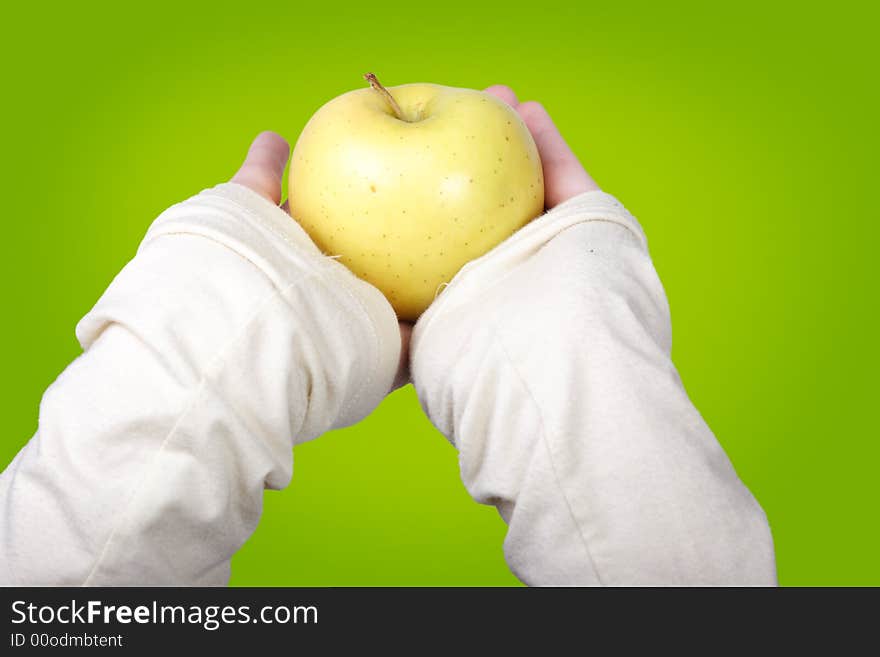 Female hands holding a yellow apple on a green background. Female hands holding a yellow apple on a green background.