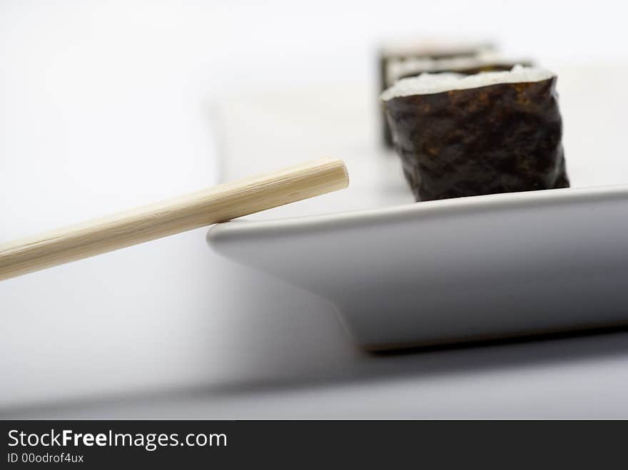 Composition of maki sushi, white late and a stick. Close focus and shallow depht of field used