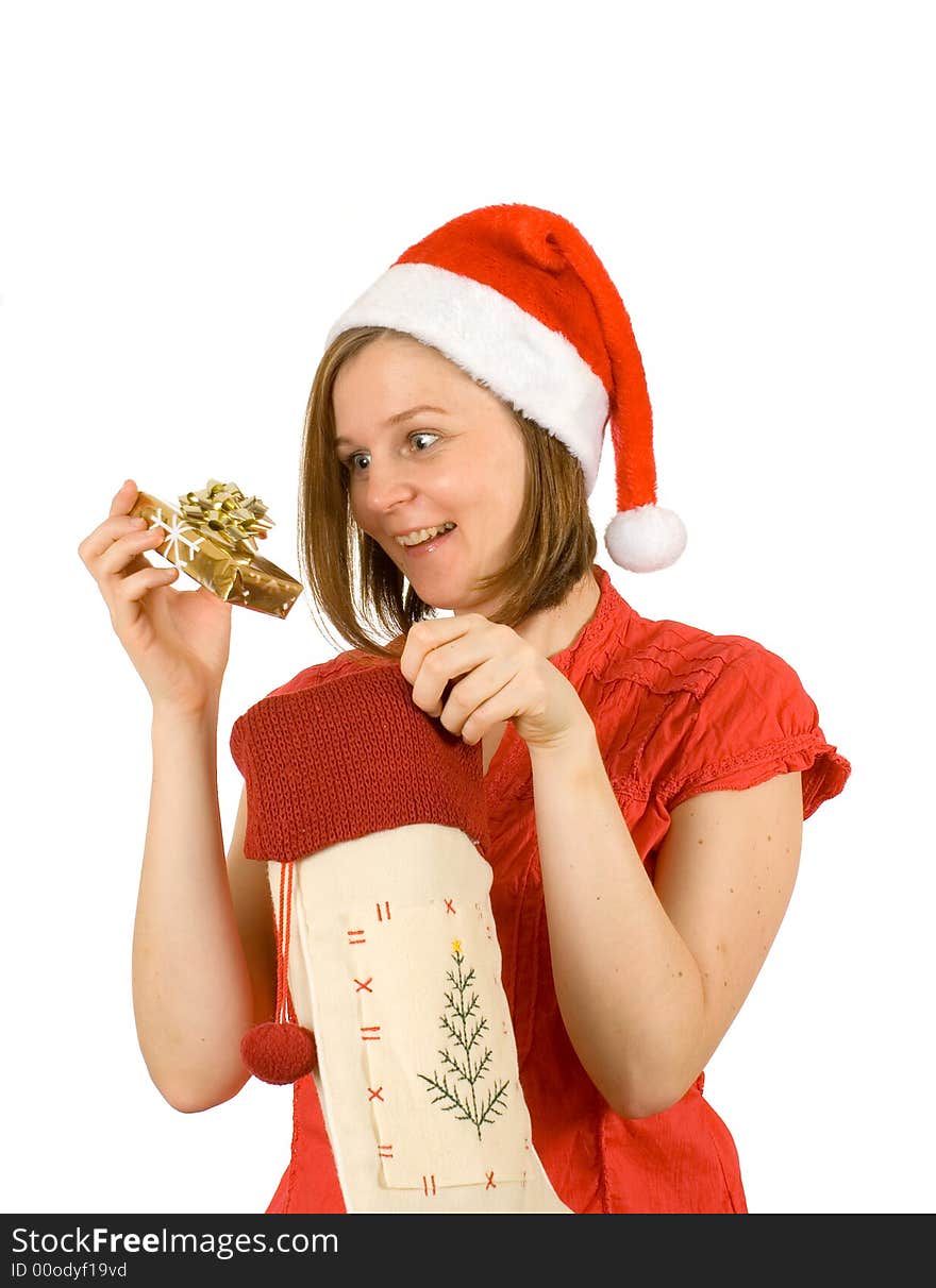 Young girl with cute smile and santa hat looking at her christmas gift in golden wrap. Young girl with cute smile and santa hat looking at her christmas gift in golden wrap