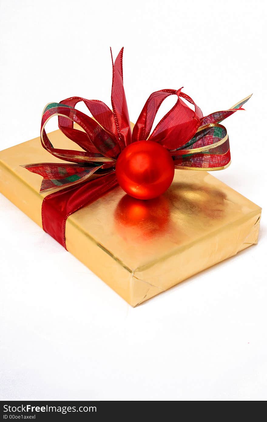 A wrapped in gold present tied with a red bow. A wrapped in gold present tied with a red bow