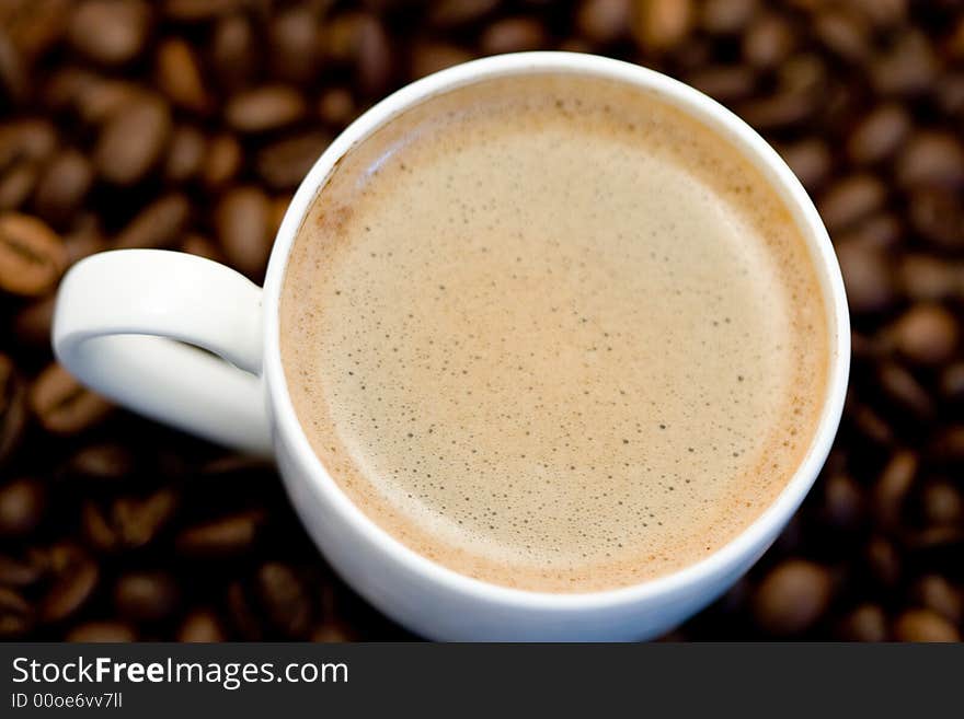 Topview of a coffee cup and coffeebeans under the cup. Topview of a coffee cup and coffeebeans under the cup