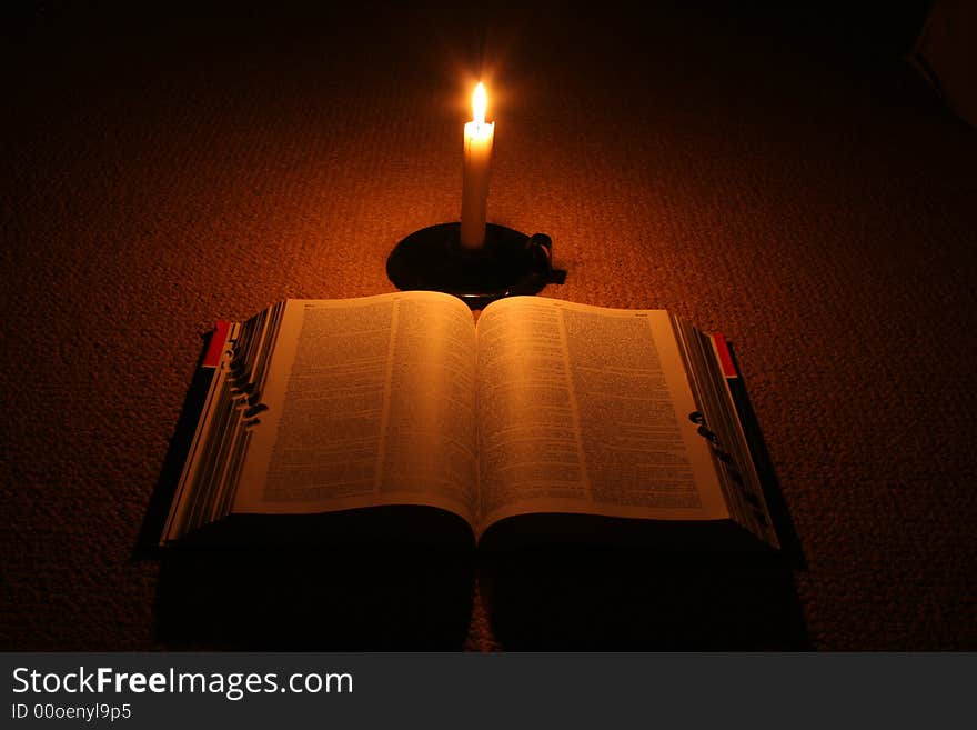 Open book in the dark with burning candle. Open book in the dark with burning candle.