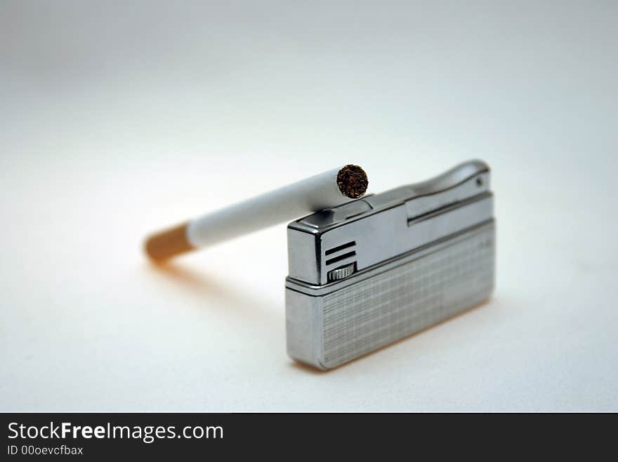 Cigarette on a lighter against a light background. Cigarette on a lighter against a light background