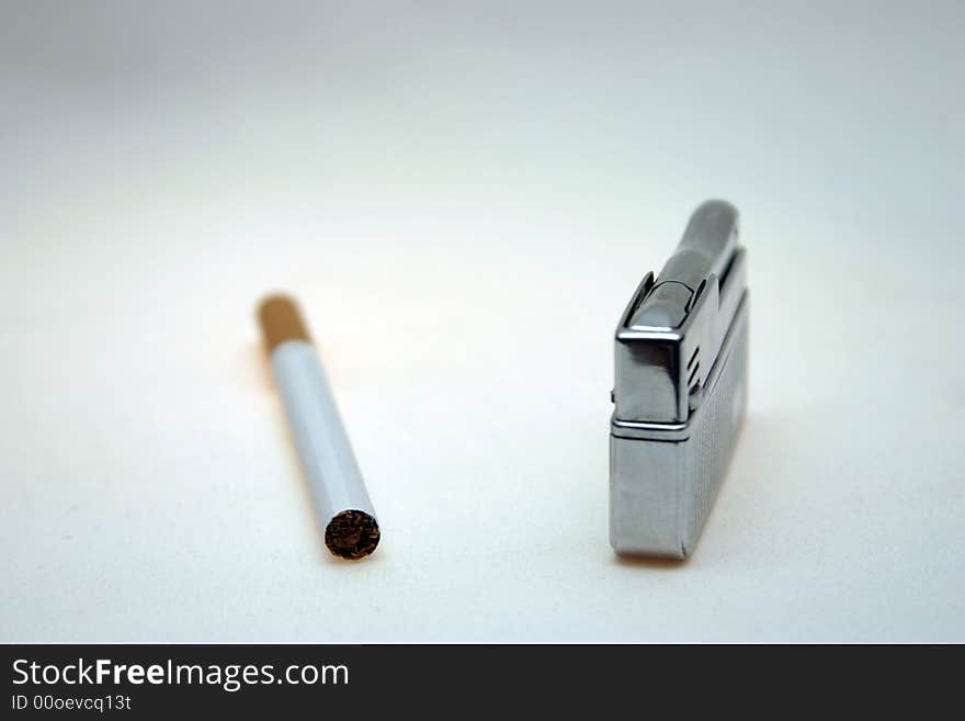 Cigarette and lighter against a light background. Cigarette and lighter against a light background