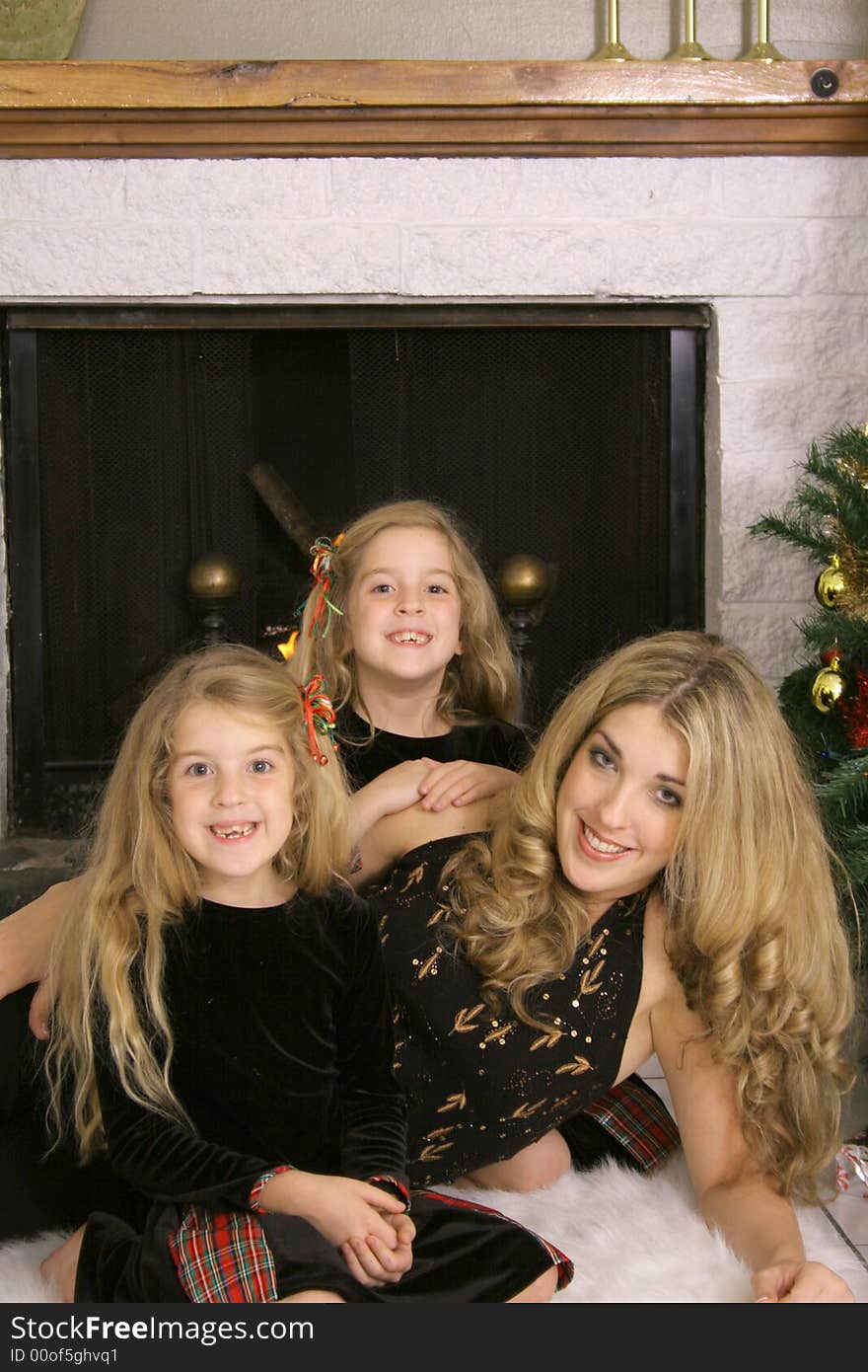 Mother with twin daughters by fireplace vertical