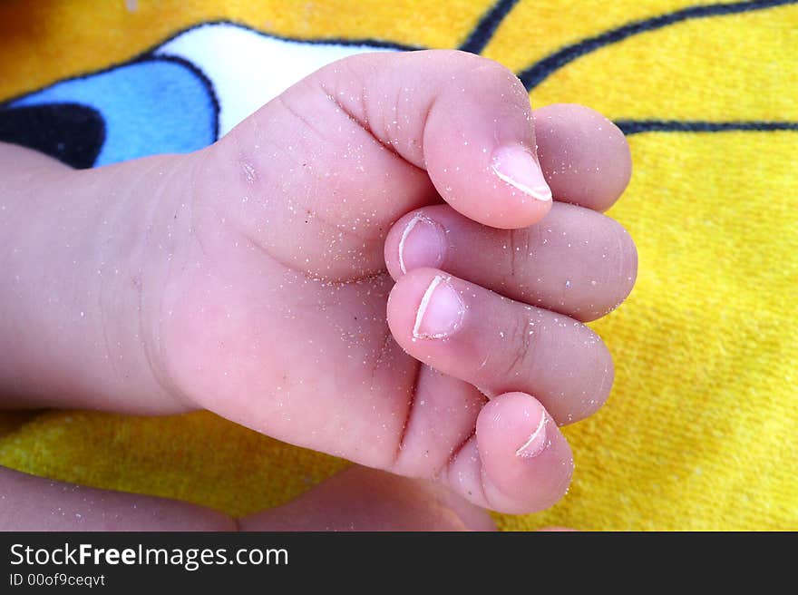 Detail of a hand of a baby on a towel at the beach. Detail of a hand of a baby on a towel at the beach