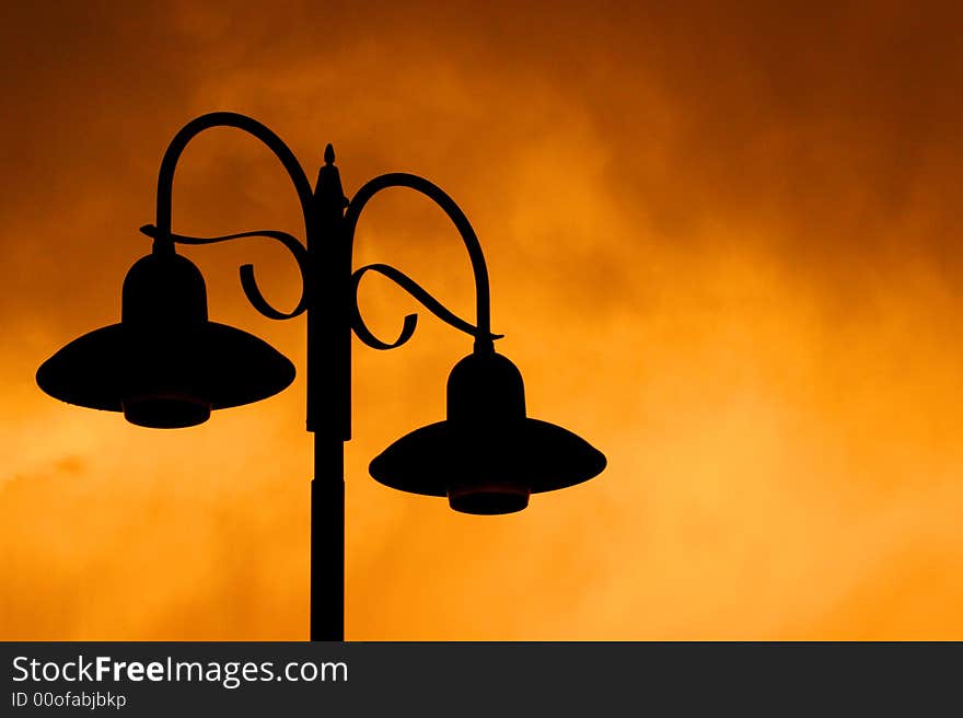 Silhouette of darken street lights against storm clouds at sunset. Silhouette of darken street lights against storm clouds at sunset.