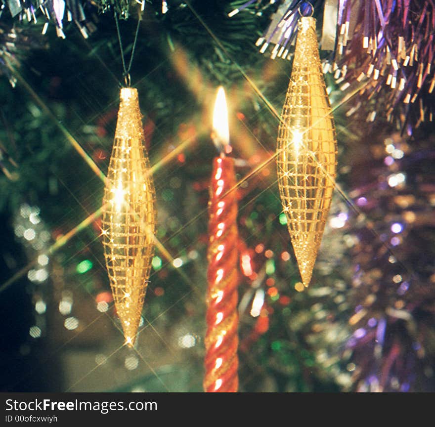 Burning candle between two fur-tree toys in the form of icicles. Burning candle between two fur-tree toys in the form of icicles