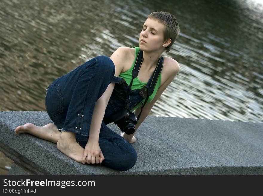 Young pretty girl with the camera resting near the river. Young pretty girl with the camera resting near the river