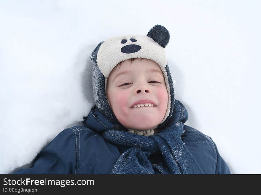 The happy boy lays in a snow