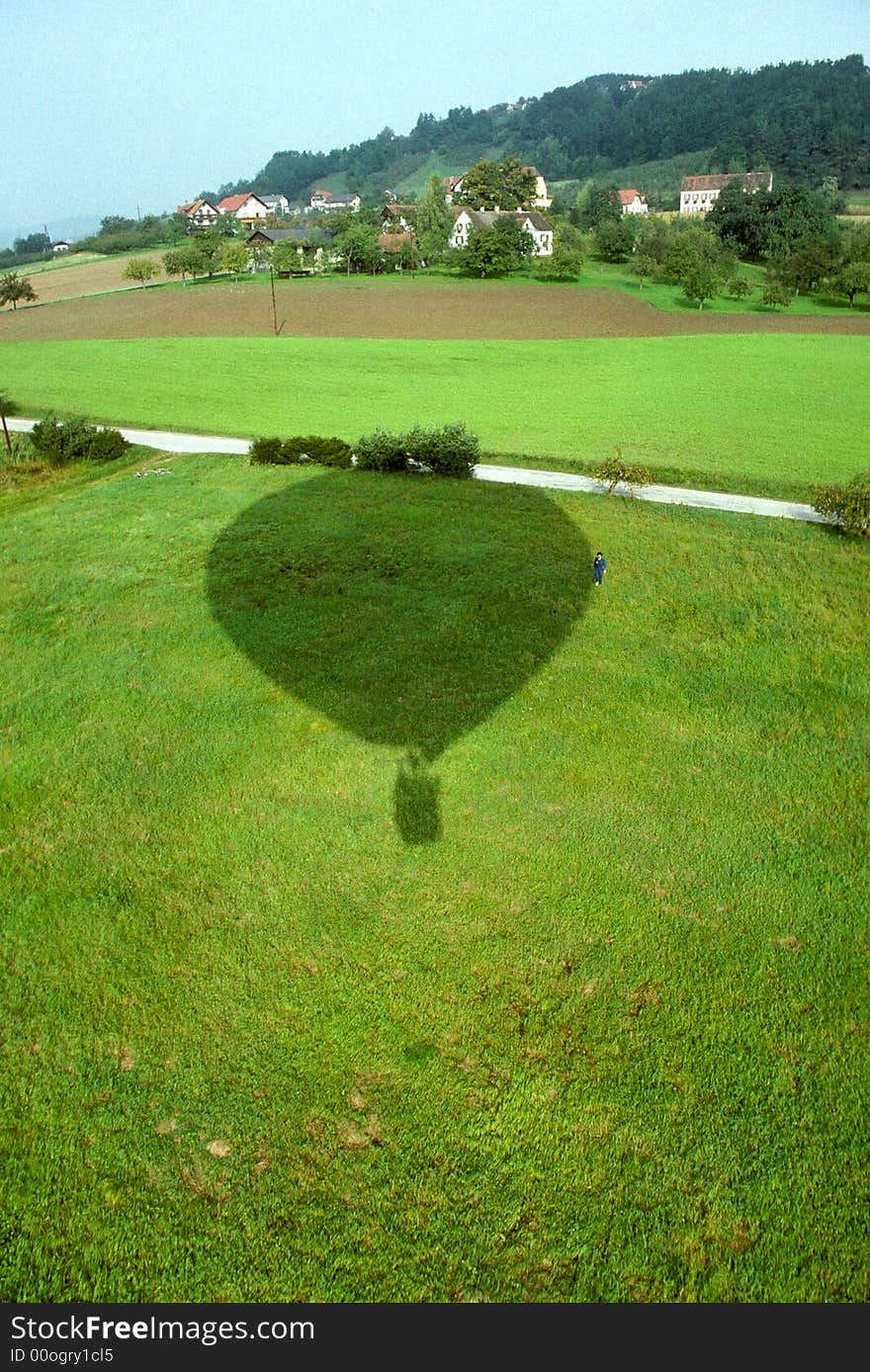 Shadow of hot air balloon about to land in field next to apple orchard. Shadow of hot air balloon about to land in field next to apple orchard