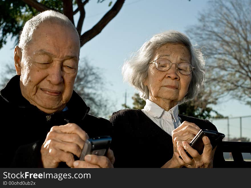 Grandma is sneaking a peak of Grandpa's handheld computer as he enters data to the device. Grandma is sneaking a peak of Grandpa's handheld computer as he enters data to the device.