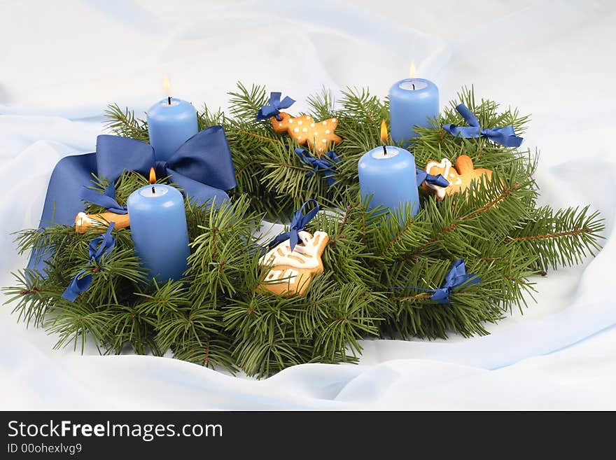 Advent wreath with blue candles, ribbon, gingerbread cookies