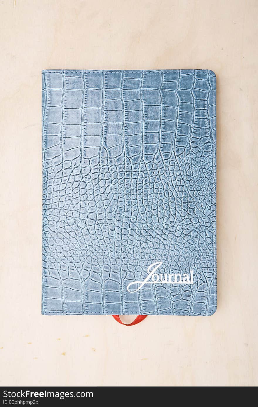 Cover of a light blue lizard skin journal note book book photographed directly above sitting on a wood table. Cover of a light blue lizard skin journal note book book photographed directly above sitting on a wood table.