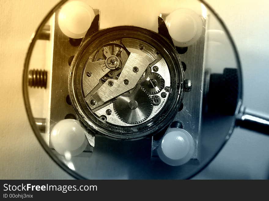 A view with a watch mechanism under a magnifier glass. A view with a watch mechanism under a magnifier glass