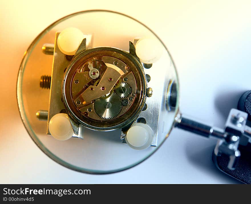 A view with a watch mechanism under a magnifier glass. A view with a watch mechanism under a magnifier glass