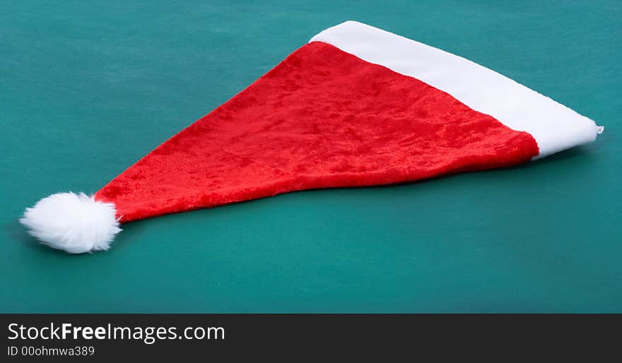 A red christmas hat over a green background