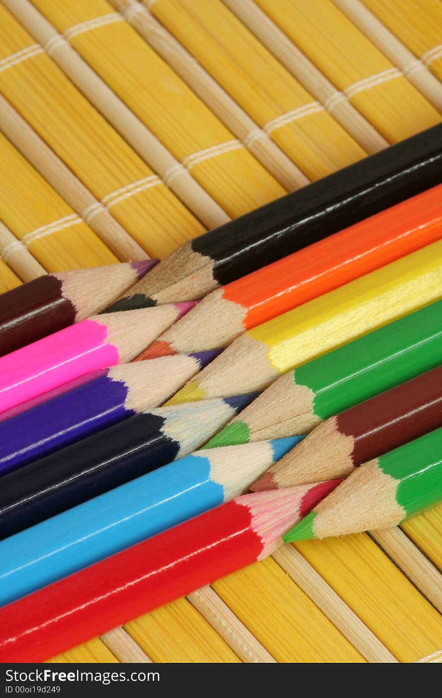 Colorful crayons on yellow bamboo mat. Colorful crayons on yellow bamboo mat