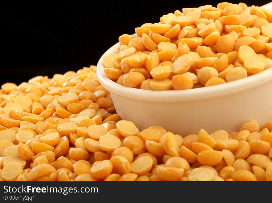 A close up of a measuring cup full of yellow beans.