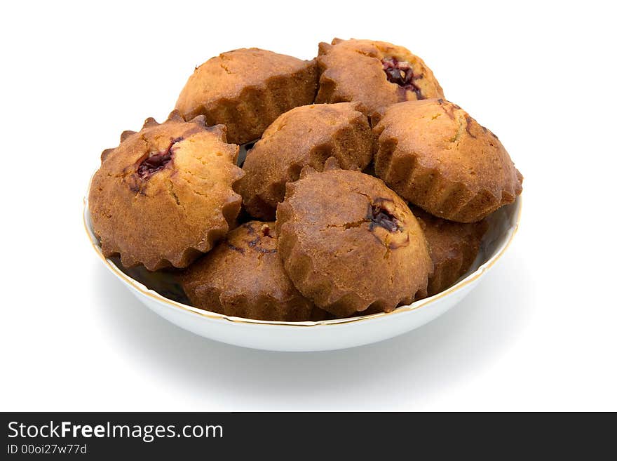 Tasty small baked cakes filled with cherry and raisins in white round bowl with shadow isolated on white. Tasty small baked cakes filled with cherry and raisins in white round bowl with shadow isolated on white