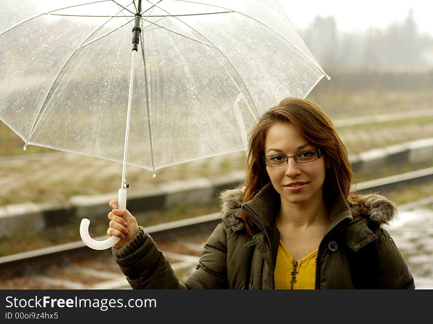 The girl with an umbrella stands under rain