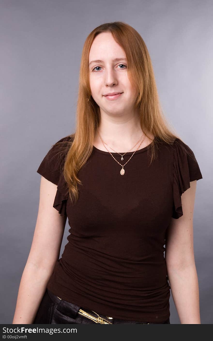 The young girl in brown shirt-blouse on a grey background