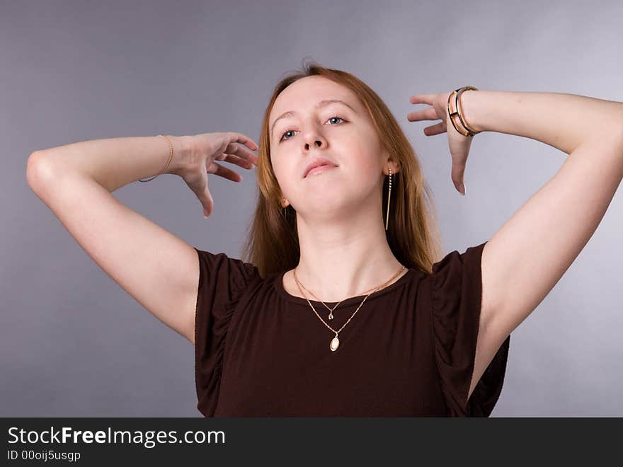 The young girl in brown shirt-blouse on a grey background