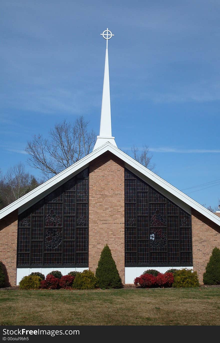 A beautiful church front showing stained glass windows and steeple.