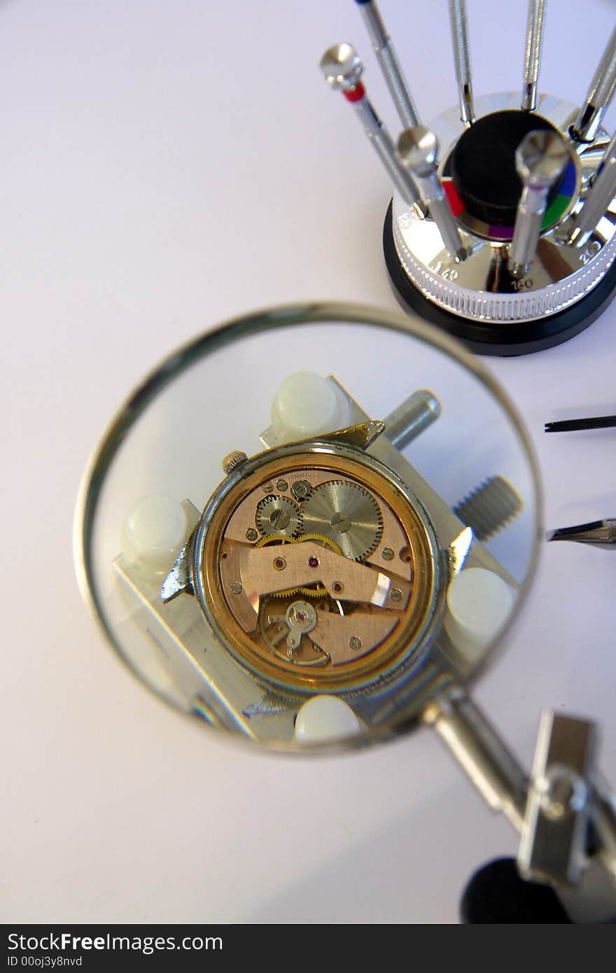 A view with a watch mechanism under a magnifier glass. A view with a watch mechanism under a magnifier glass