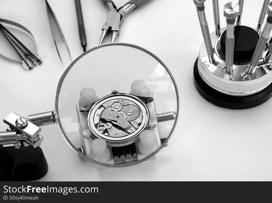 A view with a watch mechanism under a magnifier glass. A view with a watch mechanism under a magnifier glass