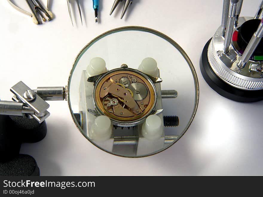 A view with a watch mechanism under a magnifier glass. A view with a watch mechanism under a magnifier glass