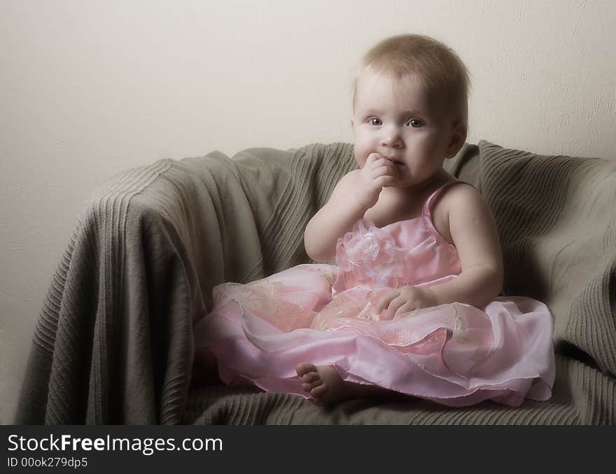 Litle girl in beautiful pink dress sitting in armchair. Litle girl in beautiful pink dress sitting in armchair