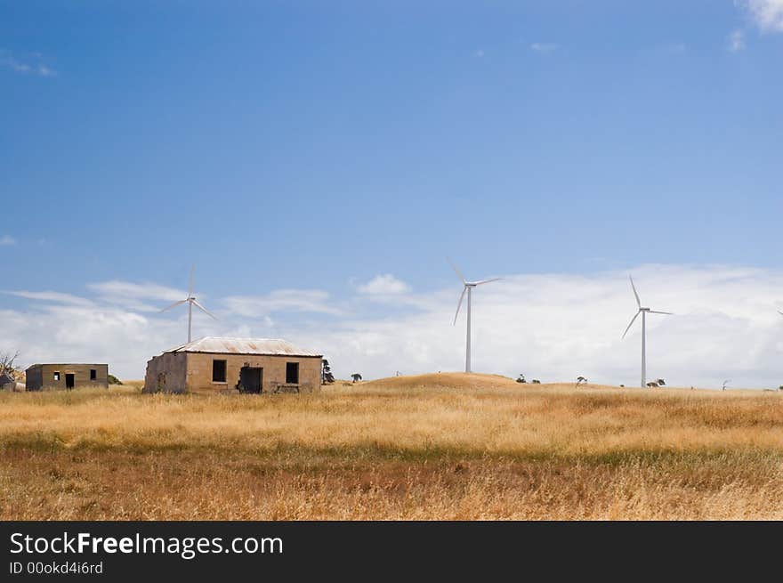 An old farmhouse and dilapidated buildings stand in front of a wind farm in South-East South Australia. An old farmhouse and dilapidated buildings stand in front of a wind farm in South-East South Australia.