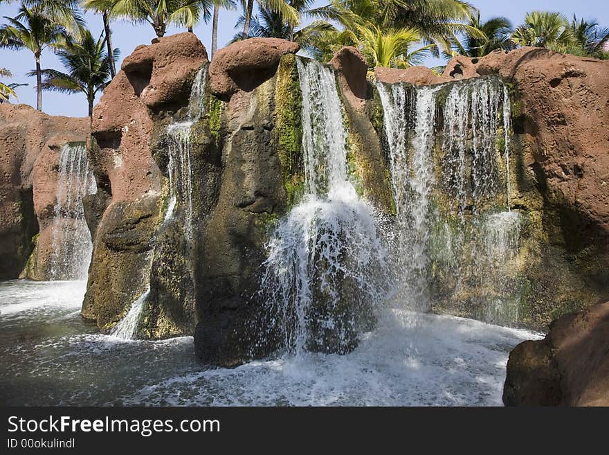 Multiple tropical waterfalls with palm tree background.