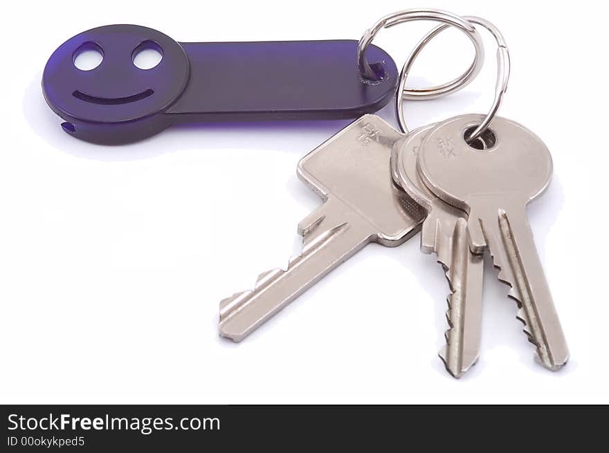 Bunch of keys with dark blue smile trinket isolated on white. Close-up. Bunch of keys with dark blue smile trinket isolated on white. Close-up.