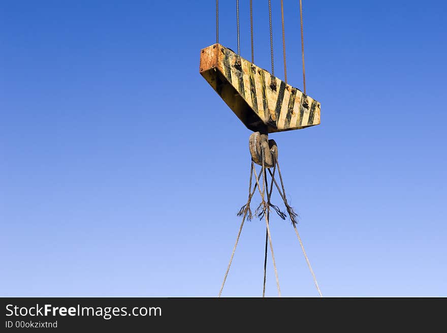 Heavy yellow striped pulley against the blue sky.