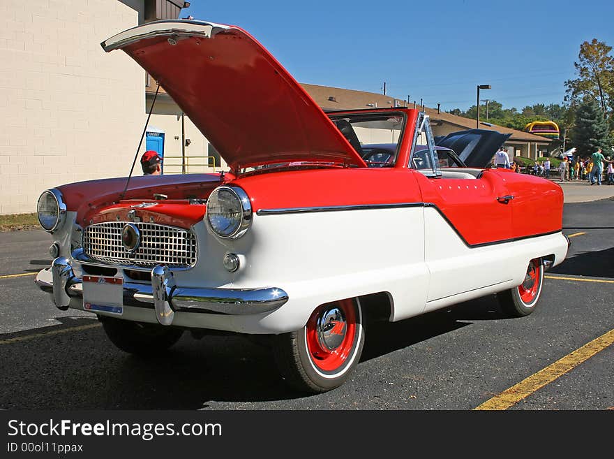 a red and white Nash Metropolitan at a car show