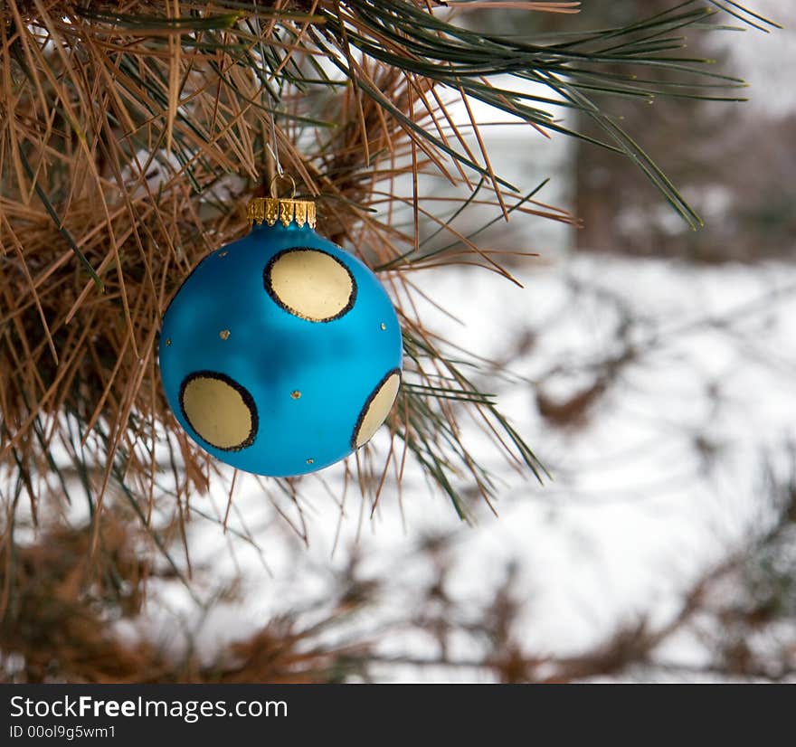 Blue and Gold Christmas Ornament in a snowy pine tree