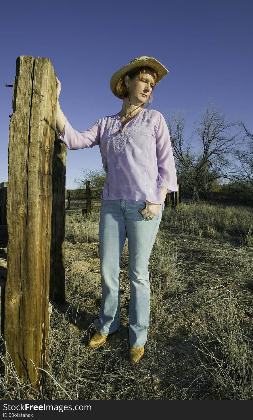 Woman wearing a cowboy hat in a rural setting. Woman wearing a cowboy hat in a rural setting.