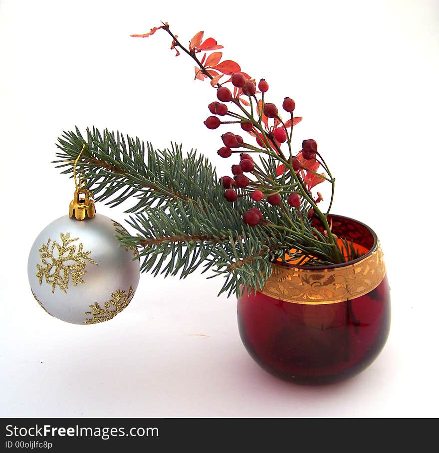 Christmas bouquet of fir-tree brunch with ball and red leaves brunch in red glass vase