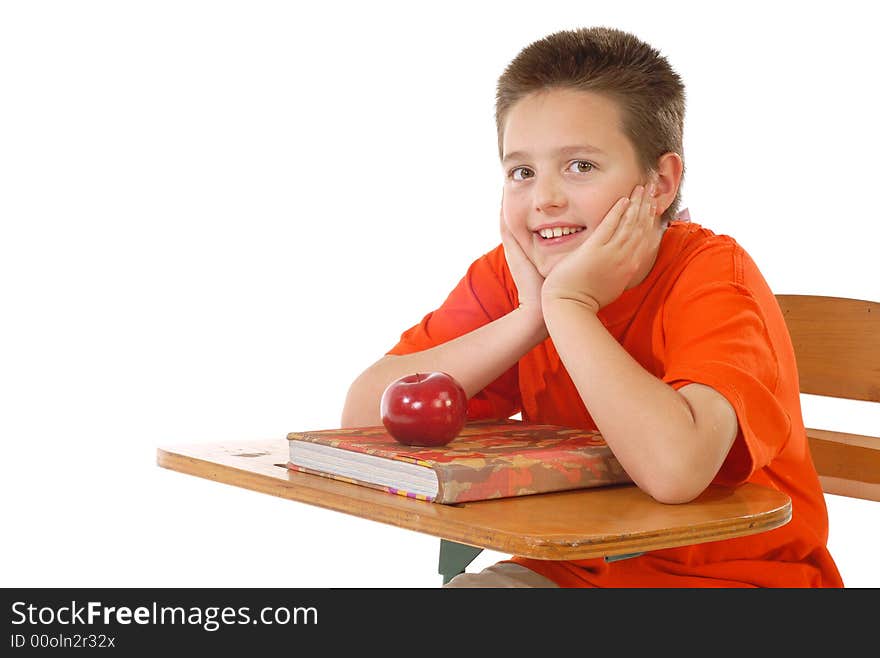 Cute schoolboy ready to learn at his desk; isolated on white