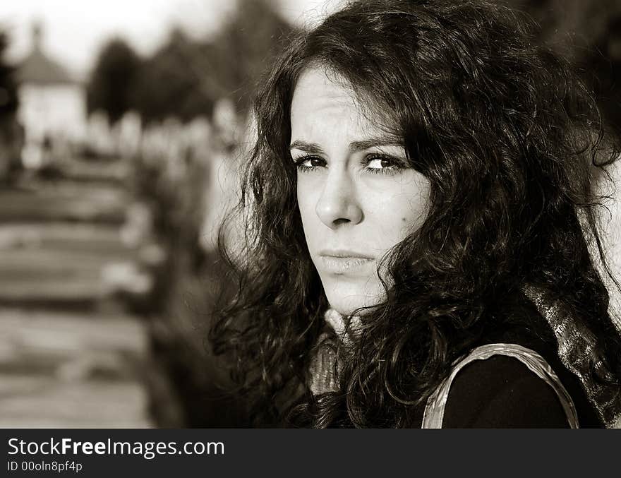 Sad woman sitting by grave in cemetery. Sad woman sitting by grave in cemetery