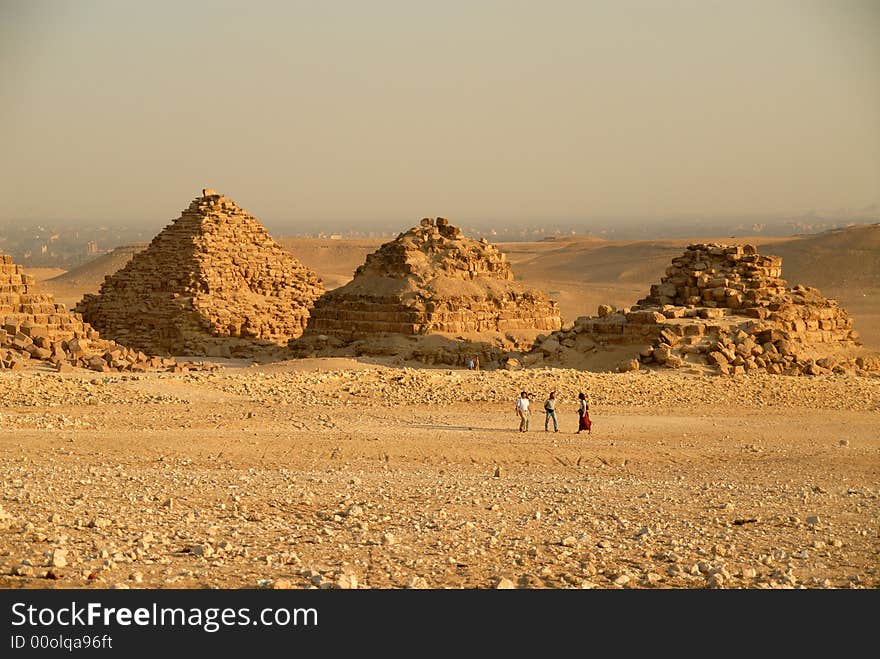 Photo of the three small pyramids at Giza in Cairo with people in the foreground to show perspective.