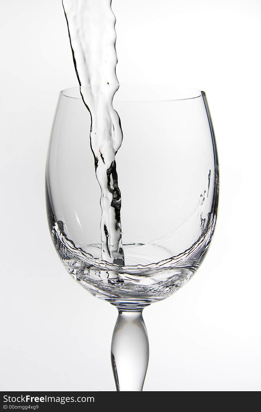 A shot of a wine glass being filled with water, white background. A shot of a wine glass being filled with water, white background