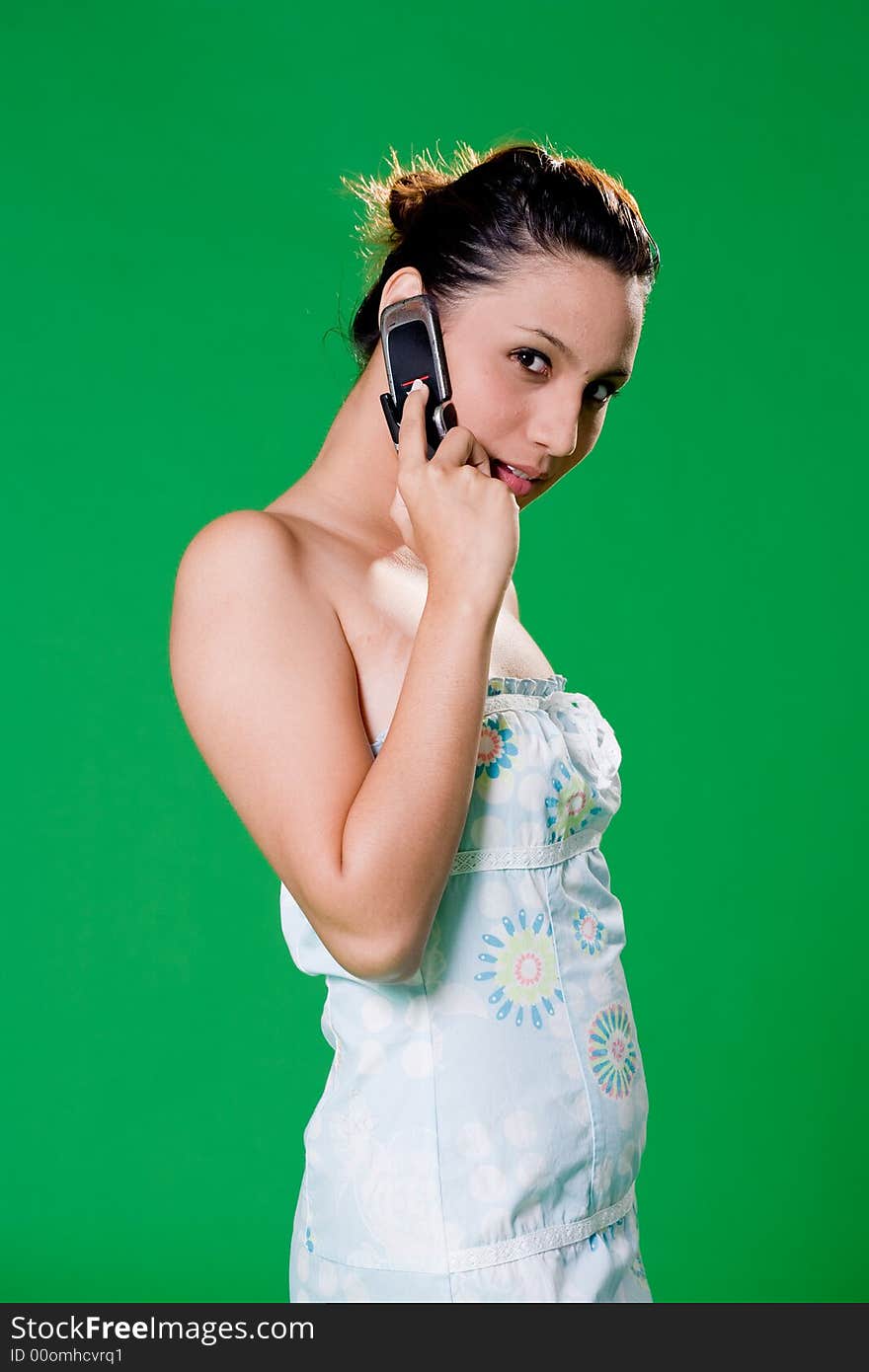 Young woman speaking on a mobile phone smiling on green background. Young woman speaking on a mobile phone smiling on green background