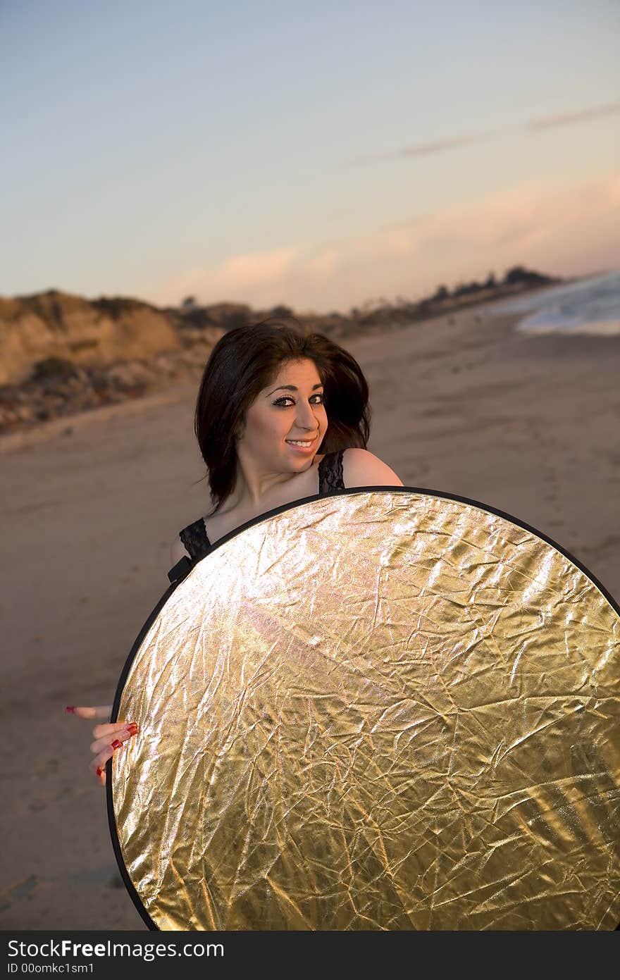 Model Holding A Reflector At The Beach At Sunset